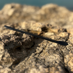 Black cosmetic spatula for mixing skincare or makeup on natural rock background