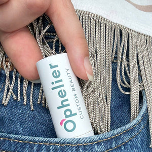 Hand placing custom beauty lipstick in denim pocket with metallic fringe detail
