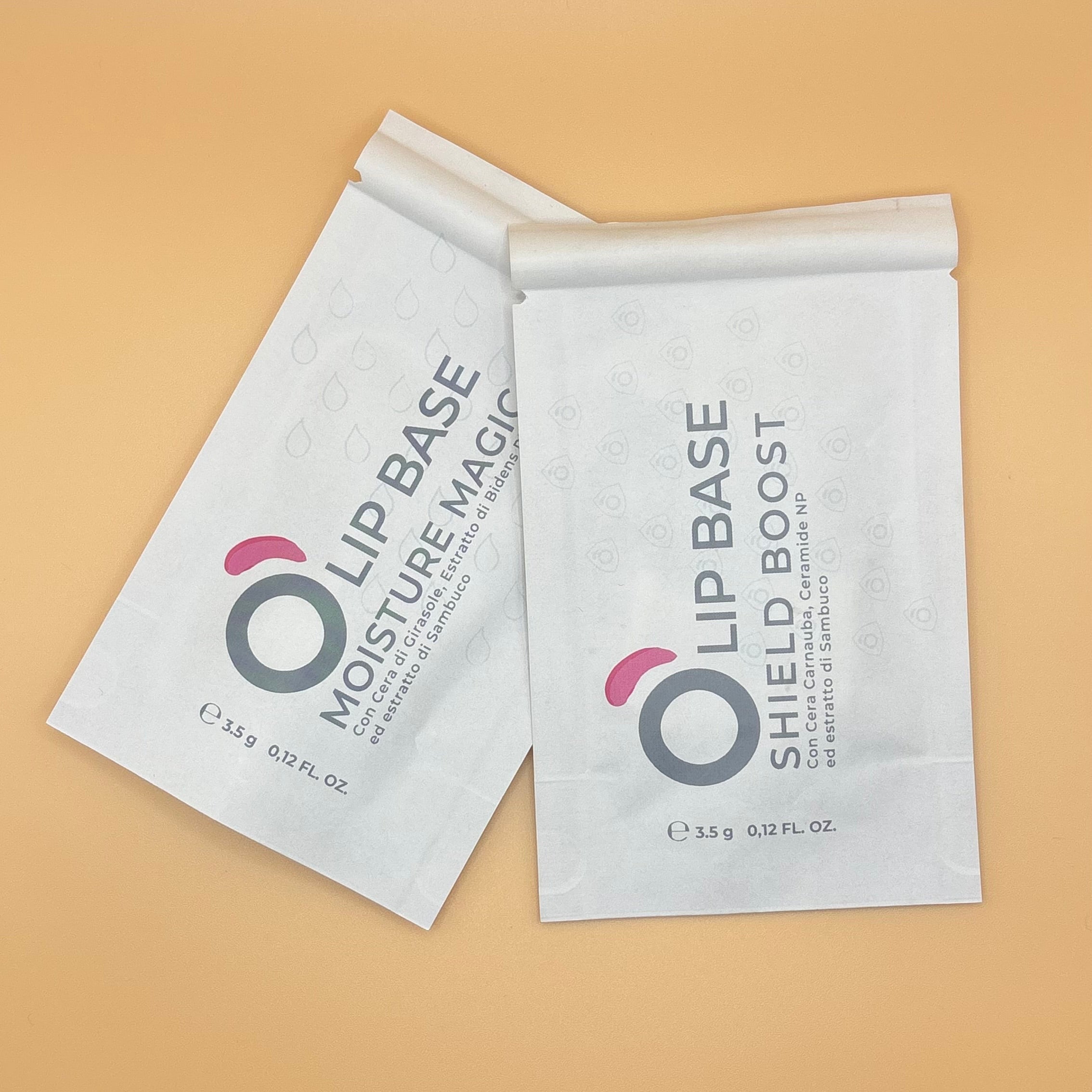 Two lip base sachets, Moisture Magic and Shield Boost, on a peach background