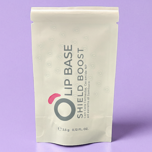 Lip Base Shield Boost vegan lip care in cream pouch on a purple background