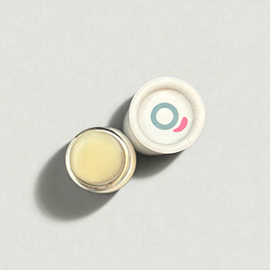 Natural vegan lip balm in small jar with white lid, viewed from above on light background