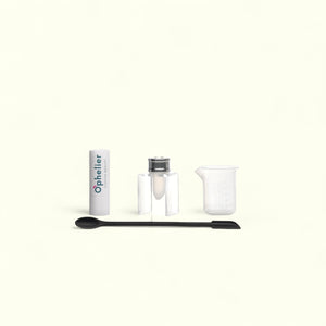 DIY beauty kit with a lipstick tube, mixing container, spatula, and measuring beaker on white background