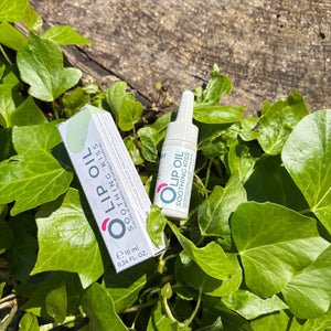 Lip oil product and box with natural formula on green ivy leaves outdoors