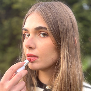 Woman applying natural vegan lipstick outdoors, close-up of lips and makeup