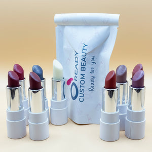 Assorted vegan lipsticks in various colors with custom beauty packaging on a neutral background