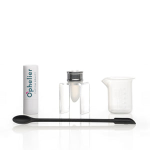 DIY vegan beauty kit with lipstick tube, mixing jar, spatula, and measuring beaker on white background
