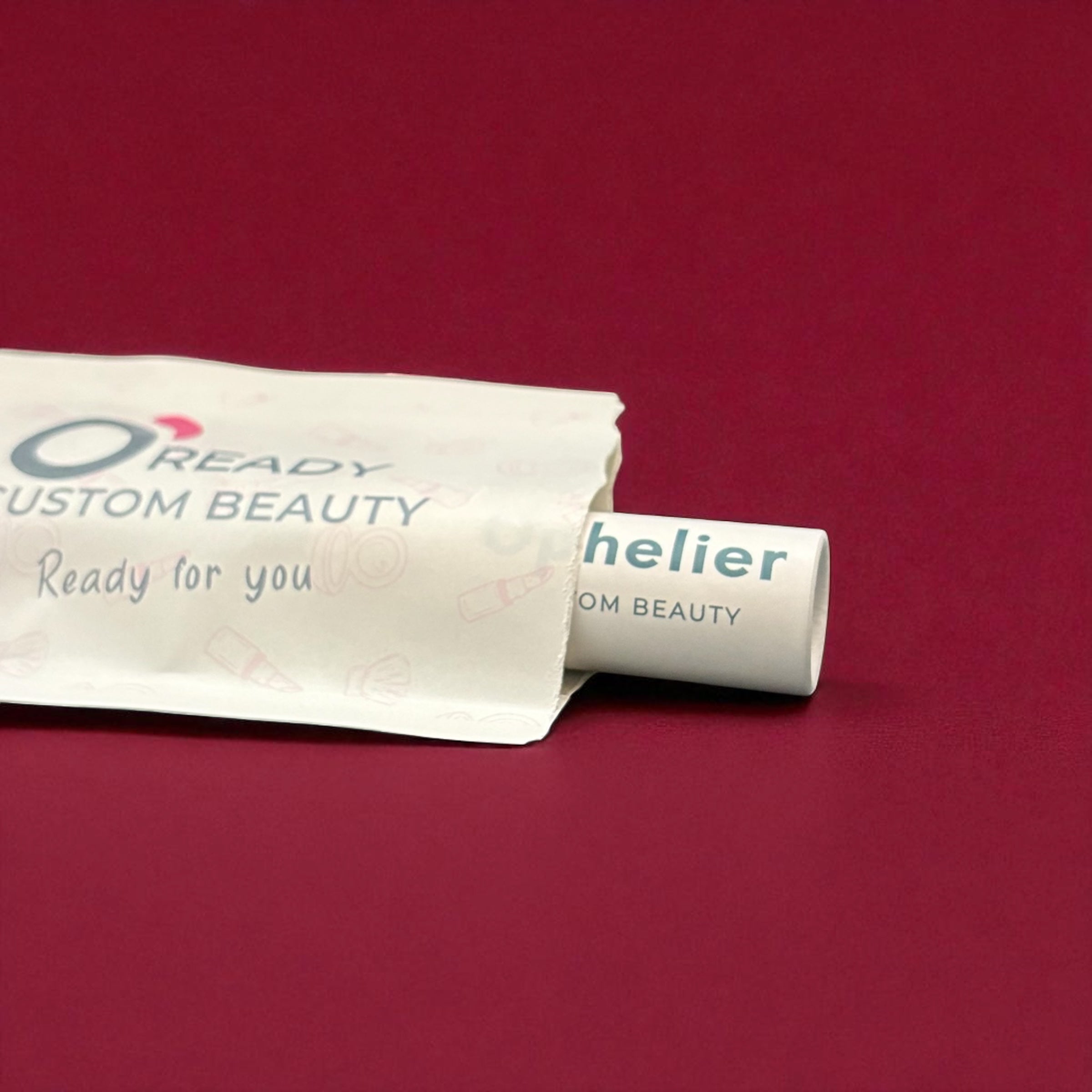 Custom beauty product tube in eco-friendly packaging on burgundy background